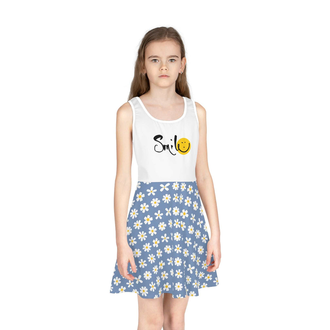 Girl wearing a sleeveless sundress with a white top featuring "Smile" text and a smiley face, paired with a blue daisy-patterned A-line skirt.