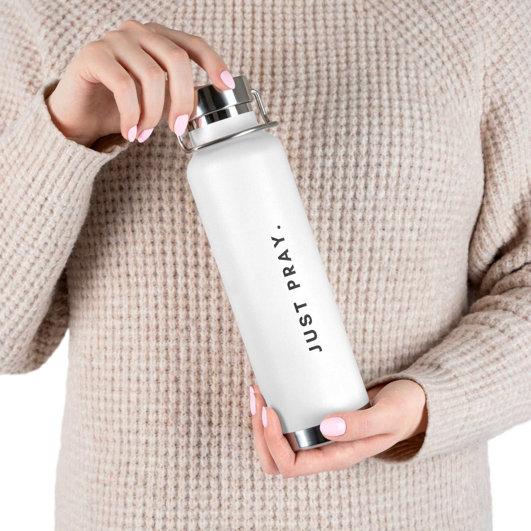 White Keep Praying bottle with spill-proof stainless steel cap held by person in beige sweater