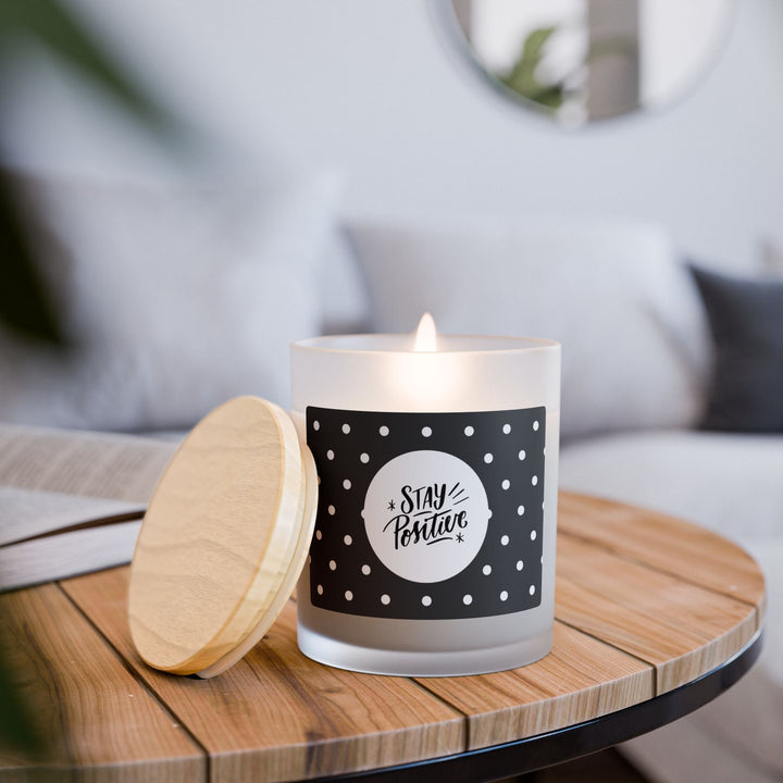 Lit Stay Positive glass candle with wooden lid on wooden table in cozy room