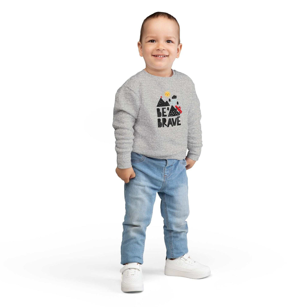 Toddler wearing a gray Be Brave sweatshirt with mountains and text