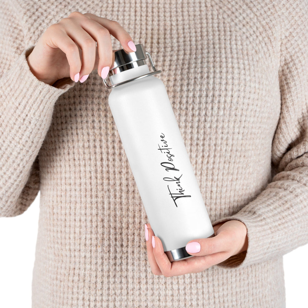 White positive mindset bottle with "Think Positive" text held by person in beige sweater, 22oz spill-proof design