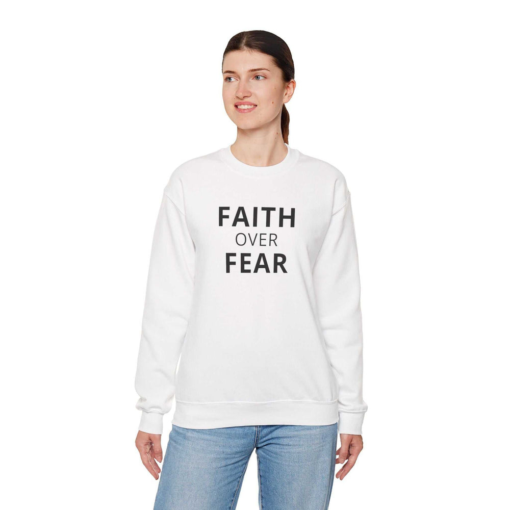 Woman wearing white Faith Over Fear sweatshirt with bold text and classic fit paired with blue jeans