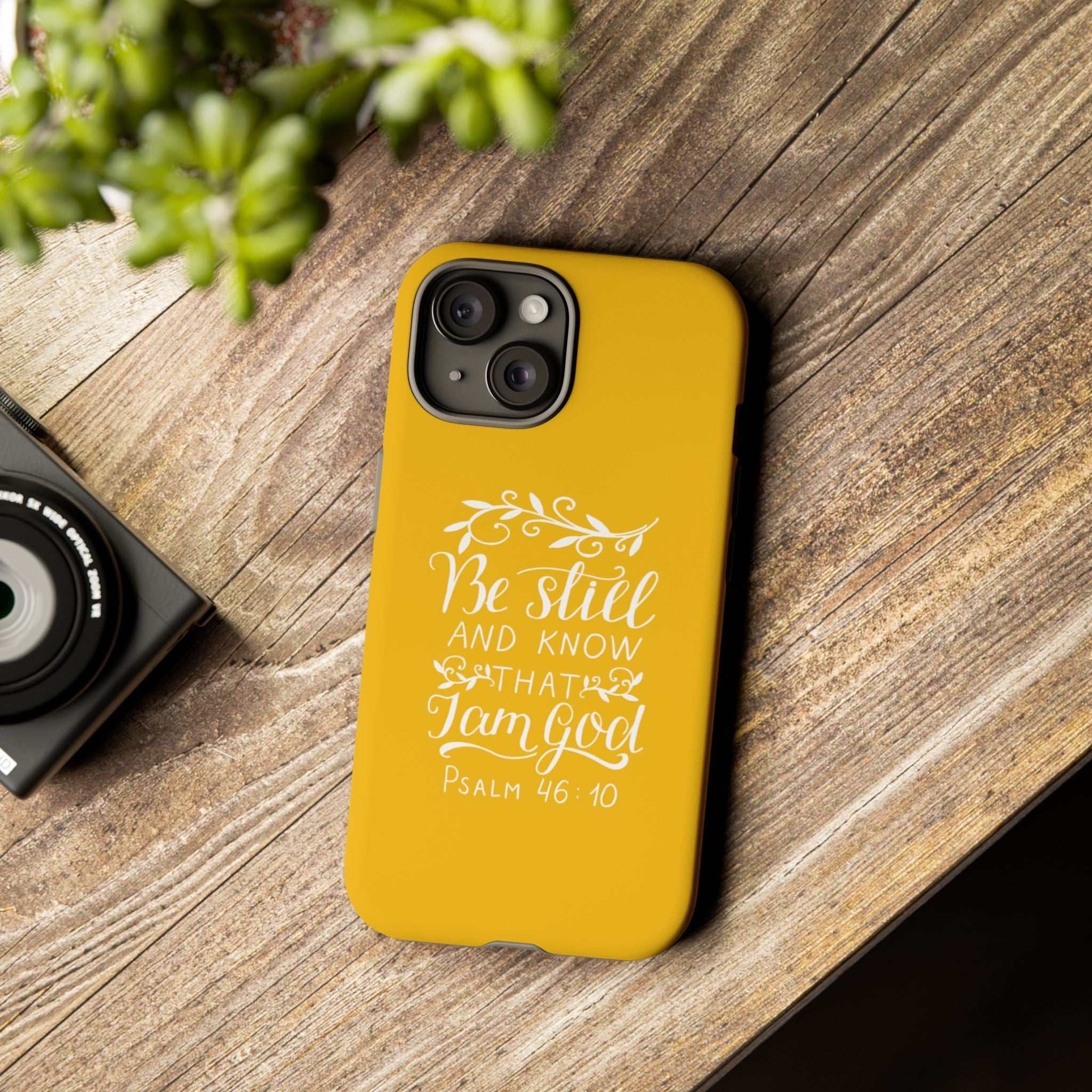 Yellow Bible quote phone case with Psalm 46:10 on wooden surface