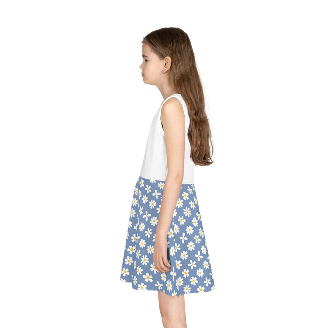 Girl wearing a sleeveless sundress with a white top and blue skirt with white daisy print, mid-length A-line cut.